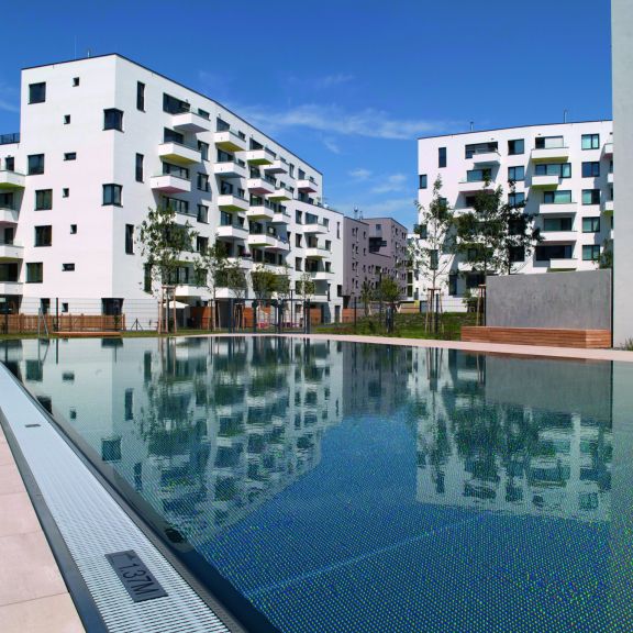 Seestadt Aspern sich vom Pool Richtung Gebäude mit weißer Fassade © Gesiba