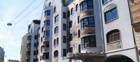 Graue Fassade mit Gemälden das Gebäude ist Herrn Arik Brauer gewidmet © Gesiba