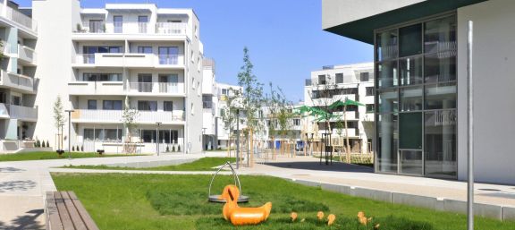 Weißes Eckiges Gebäude mit Balkonen hofseitig viel Freifläche für Kinder mit Spielplätzen schön grün. © Gesiba Weißes Eckiges Gebäude mit Balkonen hofseitig viel Freifläche für Kinder mit Spielplätzen schön grün. © Gesiba